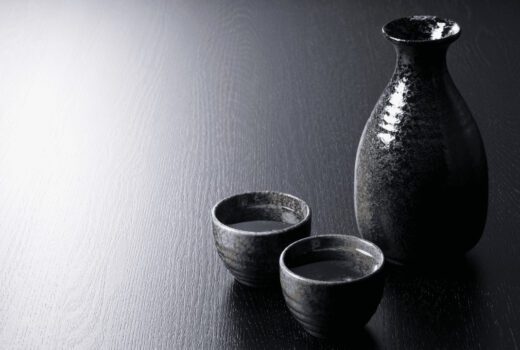 Black wood table with a ceramic sake bottle and 2 sake cups